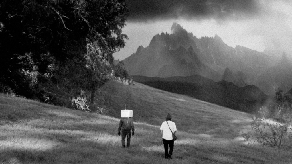 A black and white still from OBEX showing Conor and Victor walking towards a mountain.